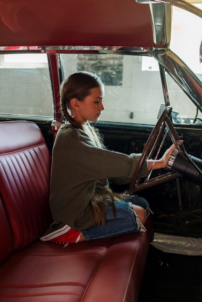 Woman in Gray Sweater Sitting on Red Leather Car Seat