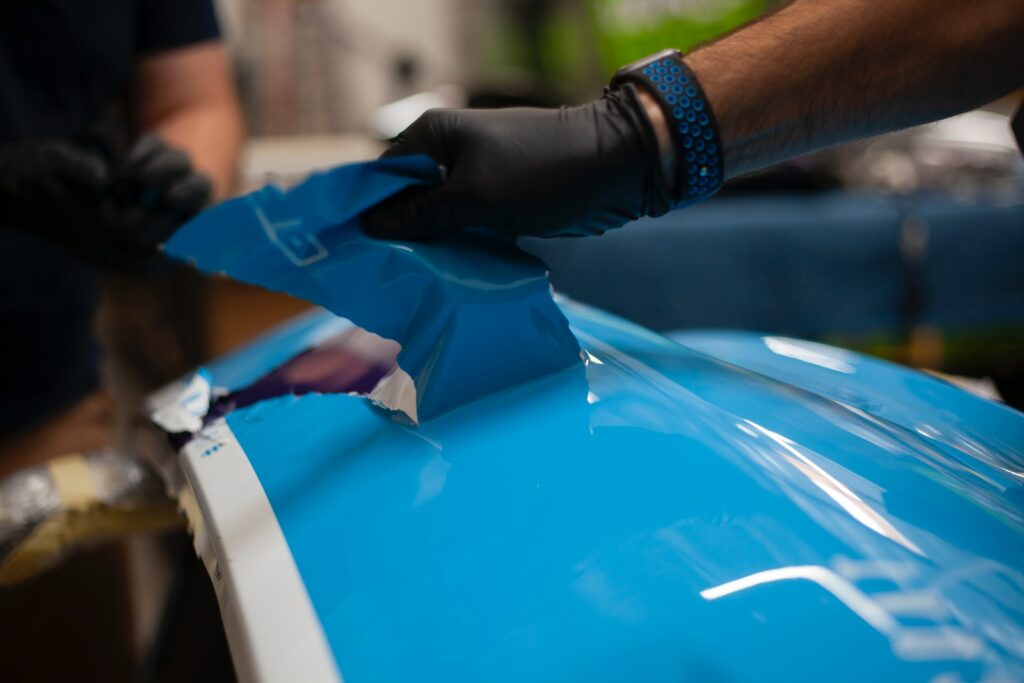 a person wearing gloves and gloves is painting a blue car